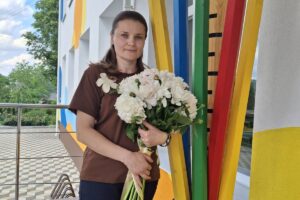 Юлія Петрівна Діденко — вчителька ОЗО «Білогородський ліцей №1» із букетом біля декоративних олівців.